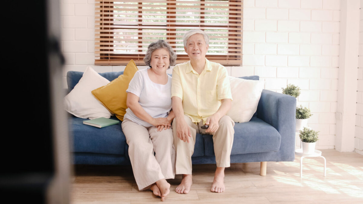 Asian elderly couple watching television in living room at home,